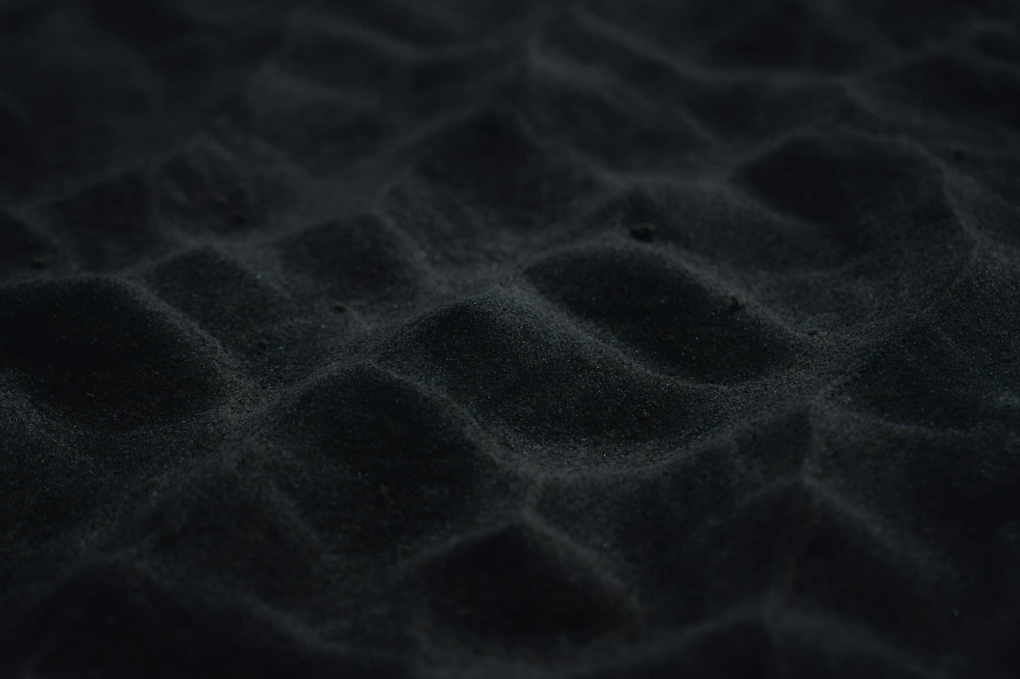 Dark ilmenite mineral sand in close-up bulk texture